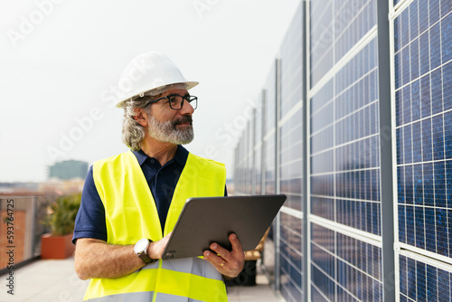Male engineer with digital tablet near solar panels photo