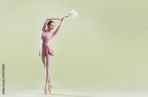 Fototapeta Naklejka Na Ścianę i Meble -  elegant young ballerina in pointe shoes dancing on a gentle green background