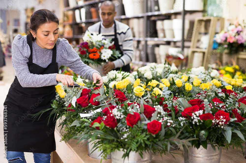 Florist in an apron creates bouquets in a flower shop