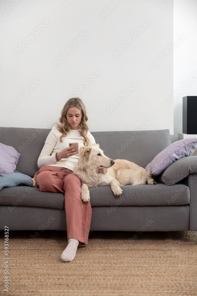 Woman texting while cuddling her White Dog on the sofa Woman texting while cuddling her White Dog on the sofa