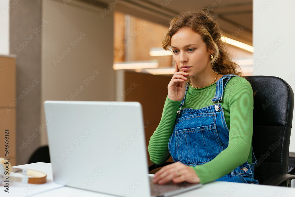 Thoughtful woman using laptop in modern office Thoughtful woman using laptop in modern office