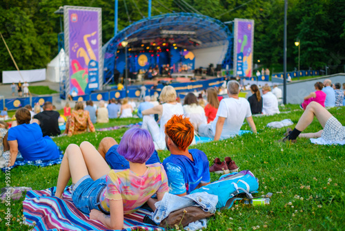 Fototapeta Naklejka Na Ścianę i Meble -  Audience sitting on plaids in park during concert