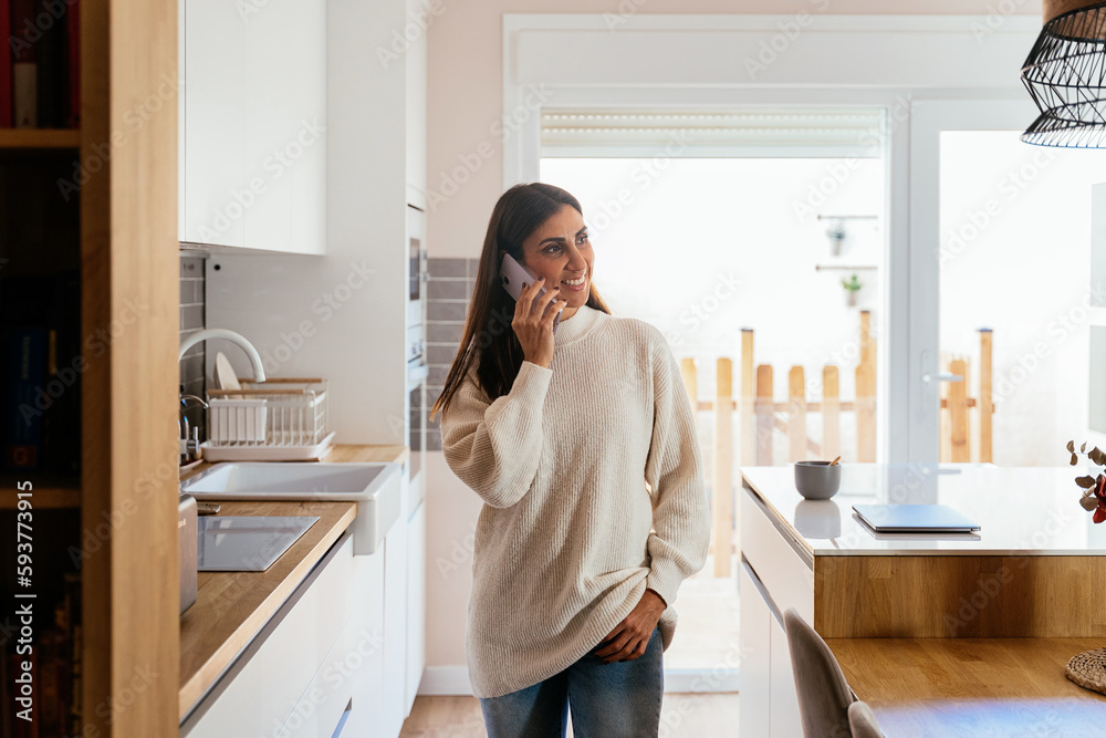 Cheerful woman having phone conversation in kitchen Cheerful woman having phone conversation in kitchen