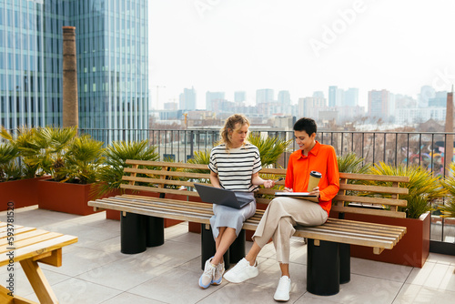 Female colleagues working together sitting in building terrace photo