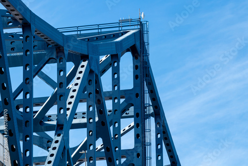 Strong angular sections of iron truss against a blue sky
