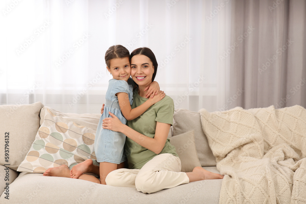 Happy woman and her cute daughter spending time together on sofa at home. Mother's day celebration Happy woman and her cute daughter spending time together on sofa at home. Mother's day celebration