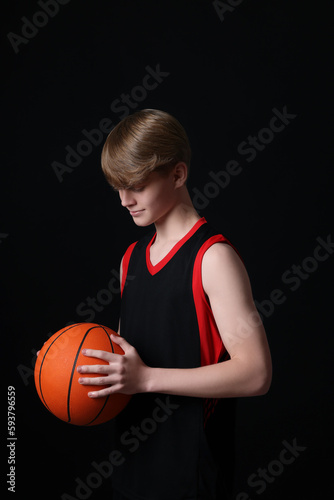 Teenage boy with basketball ball on black background © New Africa