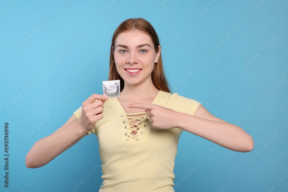 Woman holding condom on turquoise background. Safe sex Woman holding condom on turquoise background. Safe sex