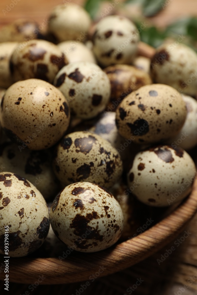 Wooden bowl with quail eggs on table, closeup Wooden bowl with quail eggs on table, closeup