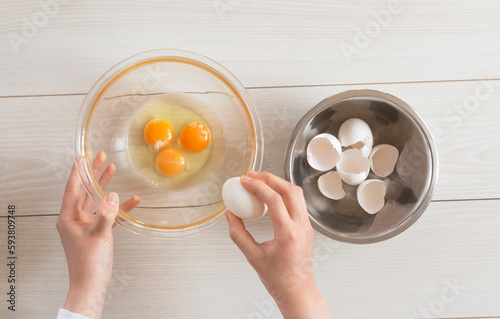 A woman cracking raw eggs into a bowl. ボウルに生卵を割る女性