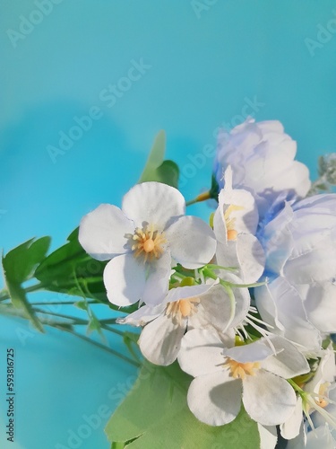Close up white simple plastic flower decoration on blue background