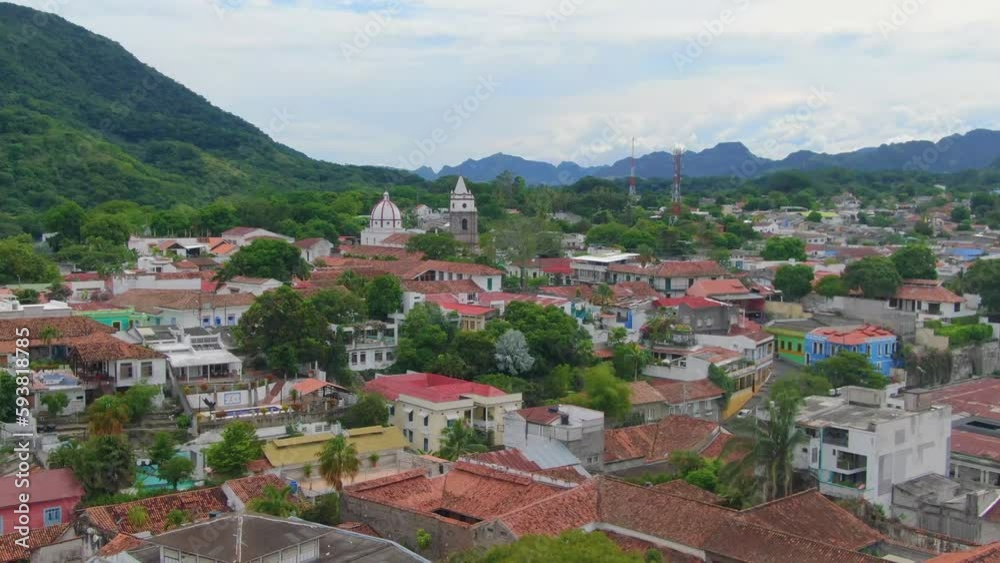 Aerial dolly zoom of vibrant city nestled in lush green mountains Aerial dolly zoom of vibrant city nestled in lush green mountains