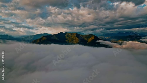 Glide above the clouds in this stunning drone footage, as majestic mountain peaks emerge in the background, providing a breathtaking backdrop to the verdant Yungas cloud forest below. photo