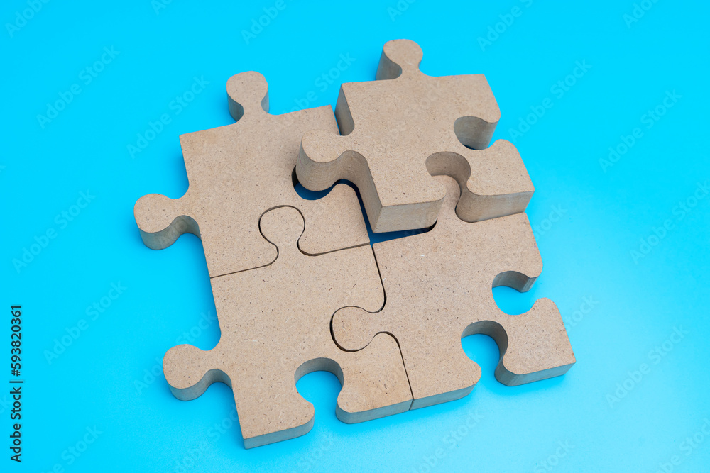 Obraz premium Wooden Jigsaw Puzzle parts on blue background. four puzzles form a rectangle on blue background. top view