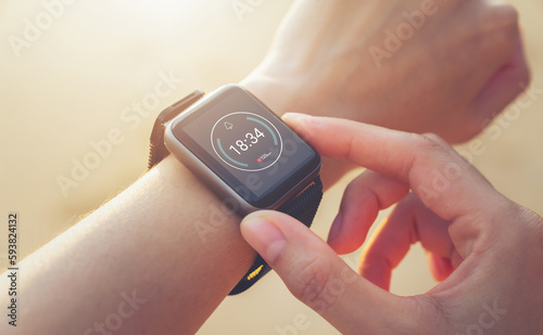 Obraz na plátně Woman hand wearing a smartwatch and checking active lifestyle and using fitness tracker outdoor on the beach