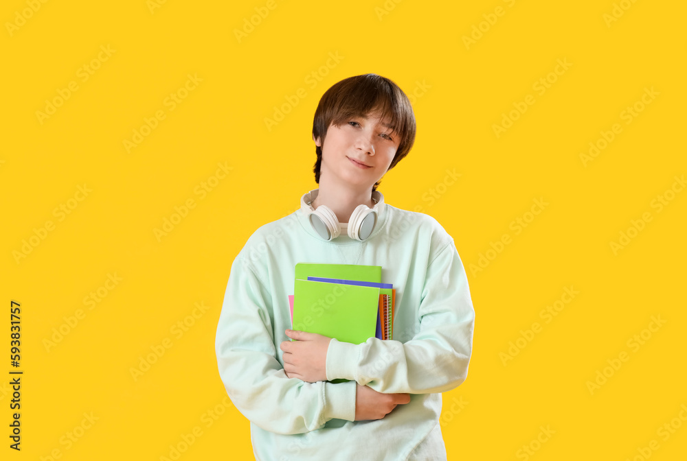 Male student with copybooks on yellow background Male student with copybooks on yellow background