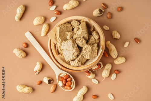 Wooden bowl of sweet halva and peanuts on color background photo