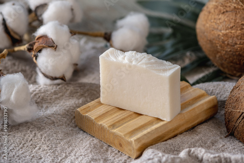 A piece of handmade white natural soap on a wooden soap dish photo