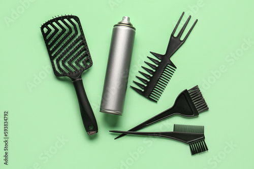 Bottle of hair spray, brush and combs on color background