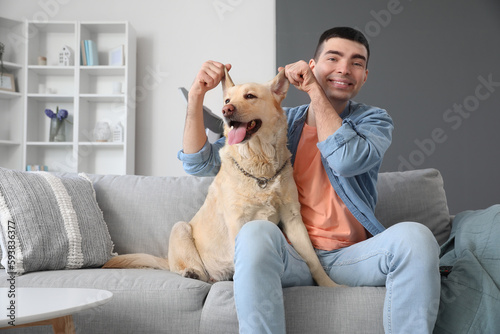 Young man with cute Labrador dog sitting on sofa at home