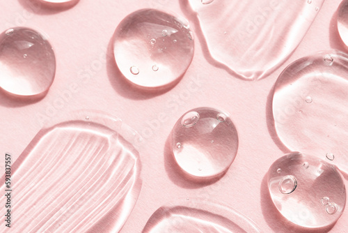 Transparent liquid gel cosmetic texture on a pink background, top view. Aloe vera gel, hyaluronic acid, peptide macro. photo