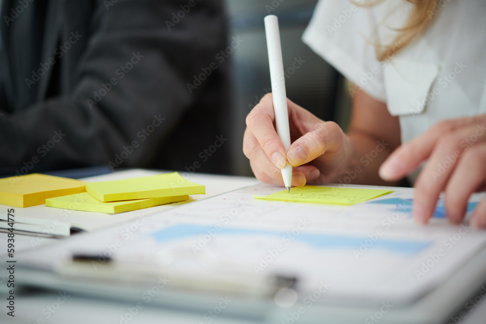 Marketing manager analyzing financial charts and writing figures on yellow sticky notes Marketing manager analyzing financial charts and writing figures on yellow sticky notes