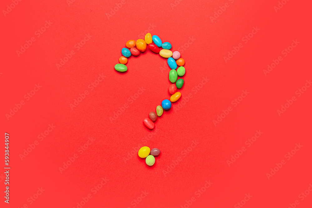 Question mark made of candies on red background