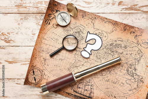 World map with question mark, spyglass, compass and magnifier on white wooden background