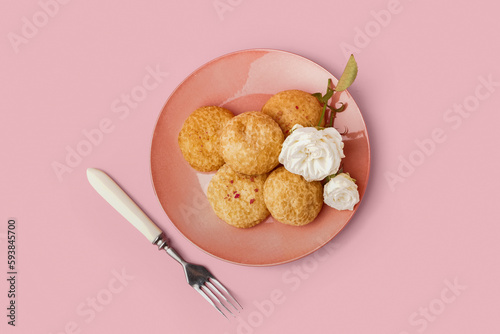 Plate with tasty choux dessert on pink background photo
