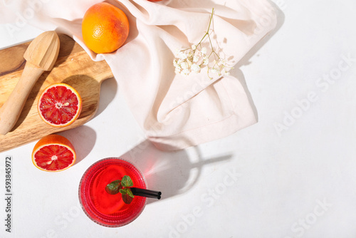 Glass of tasty blood orange lemonade and fresh fruits on light background