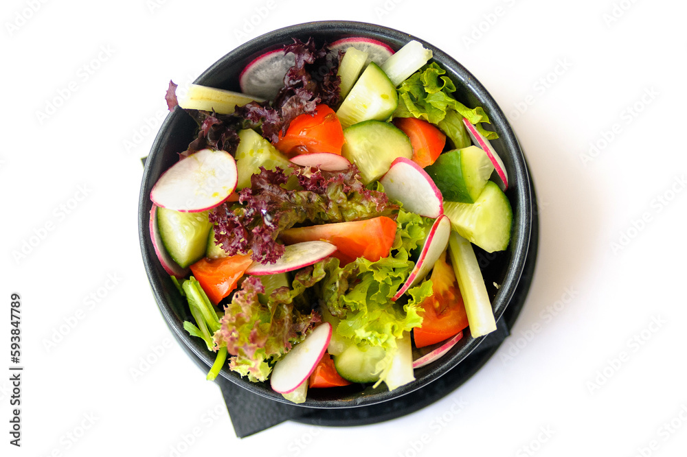 Salad of fresh seasonal vegetables in a black plate isolated
