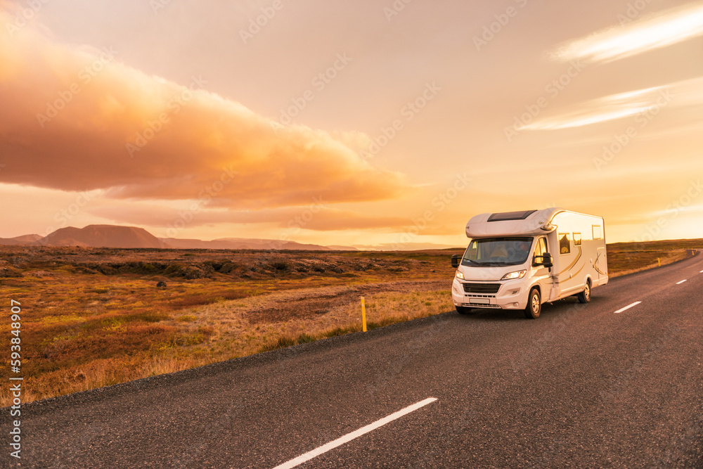RV Motorhome camper van road trip. People on travel vacation adventure. Tourists in rental car campervan by view of mountains in beautiful nature landscape at sunset. From Iceland