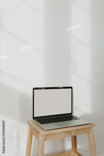 Laptop computer with empty blank copy space screen display. White wall with aesthetic sun light shadows. Online shop, store, website, social media template