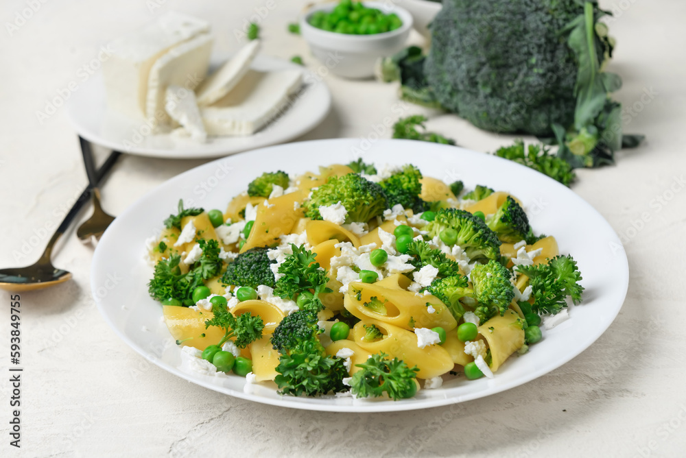 Plate with tasty penne pasta and broccoli on light grunge background Plate with tasty penne pasta and broccoli on light grunge background