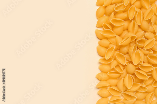 Heap of raw conchiglie pasta on yellow background photo