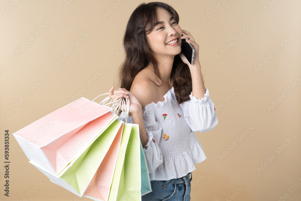 Young Asian woman usin shopping bag using phone on isolate brown background Young Asian woman usin shopping bag using phone on isolate brown background