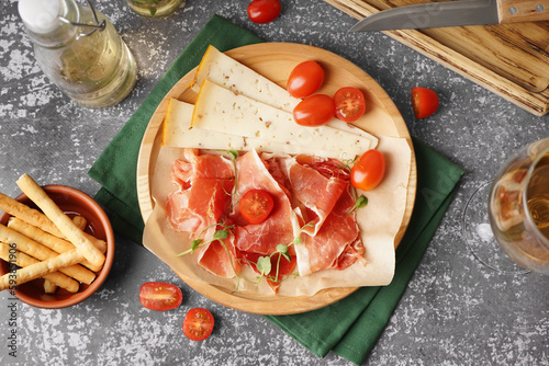 Plate with slices of tasty jamon and cheese on grunge background