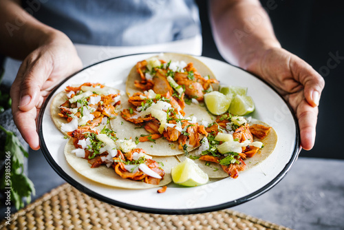 Mexican tacos al pastor on plate holding by woman hands, traditional mexican food in Mexico Latin America