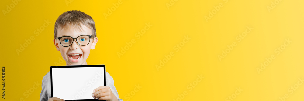 a Happy child boy holding a tablet on color background