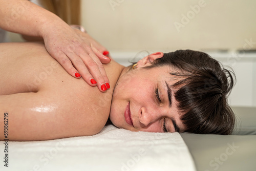 Beautiful caucasian woman client receiving relax massage on back in spa salon