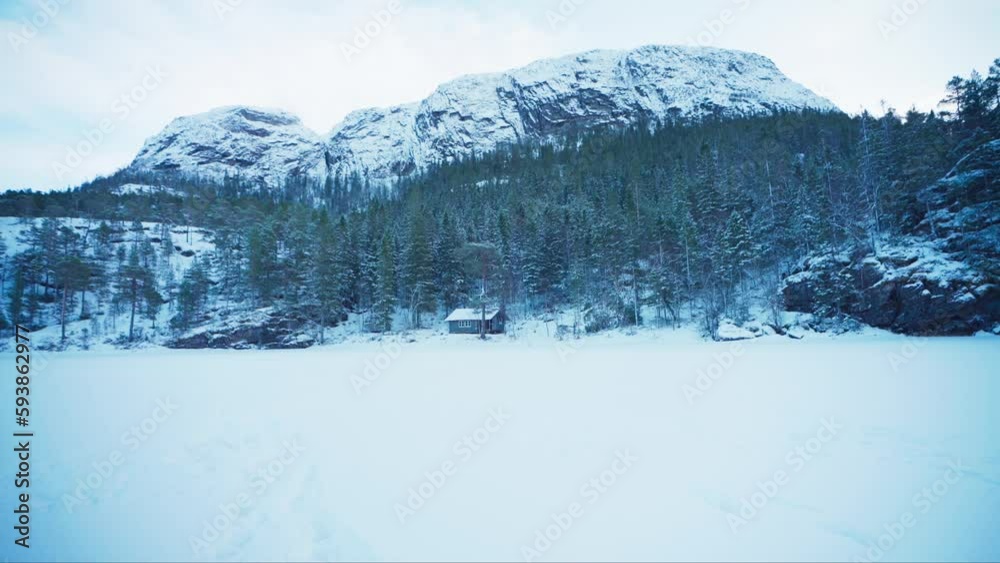 Stunning Winter Landscape With Isolated Cabin Below Snow-Covered Forest Mountain. Wide Shot Stunning Winter Landscape With Isolated Cabin Below Snow-Covered Forest Mountain. Wide Shot