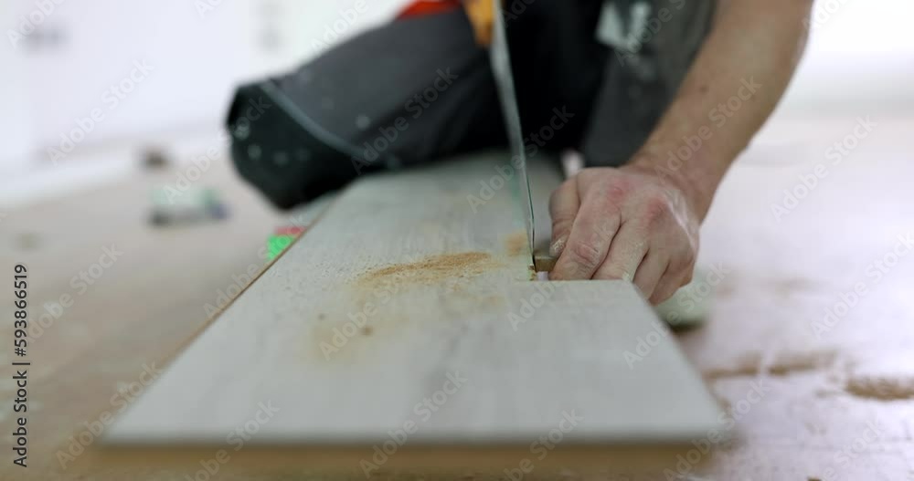 Closeup of male hands cutting parquet board with saw. Laying flooring and cutting laminate Closeup of male hands cutting parquet board with saw. Laying flooring and cutting laminate