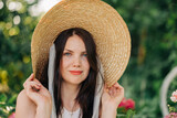 Beautiful woman with dark hair brunette wearing summer hat on vacation in the park garden portrait