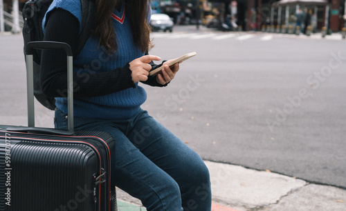 Woman with baggage in downtown city street searching location in map application online on smart phone using GPS navigating.