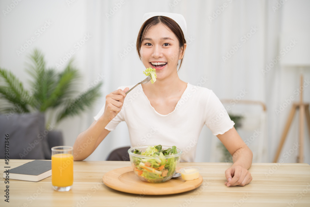 Happy beautiful Asian woman eating healthy food with vegan.salad in the kitchen at home. Happy beautiful Asian woman eating healthy food with vegan.salad in the kitchen at home.