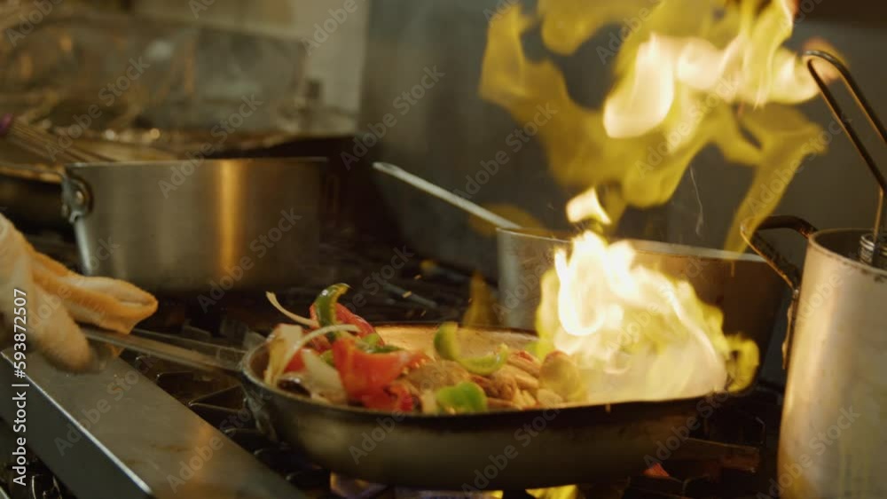Vegetables cooking sizzle fire flame saute pan oil commercial kitchen tongs