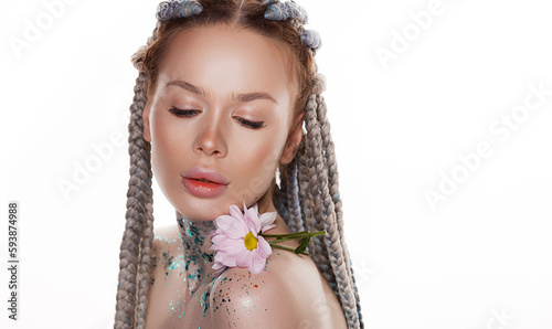 Beauty portrait of lovely young woman with healthy skin and pink flowers near face and glitter sparkles on her face, neck and shoulders over white background