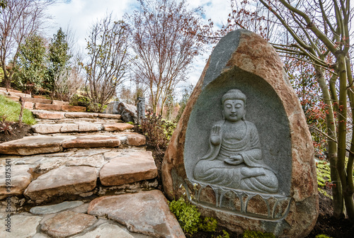 a stone with a Buddha image on a path in a Japanese garden