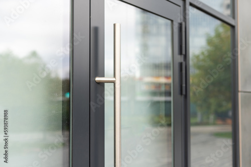 The front door of a office block, reflecting buildings in the glass