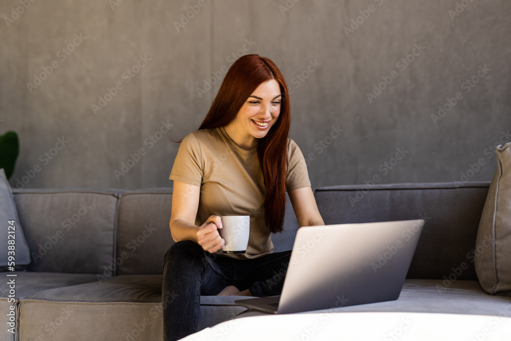 Young woman wear casual site on couch drink tea use laptop relax think the idea full of plants in living room indoor plants at home